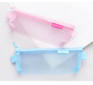 Close-up detail of pink and blue mesh pencil cases resting on an open book background
