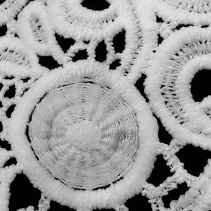 Macro detail view of white water-soluble milk silk lace with 3D embroidery pattern.