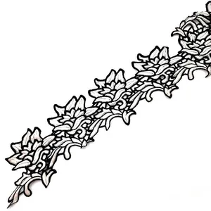 Detailed view of white water-soluble lace trim with black embroidered flower motifs.