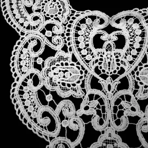 Detailed macro view of white water-soluble embroidered lace collar with fine hollow patterns