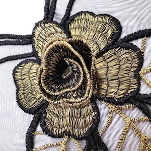 Close-up detail of a luxurious gold and black embroidered rose lace flower patch