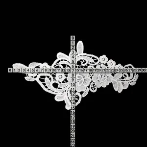 Detailed macro view of white milk silk floral lace applique with ruler measurements