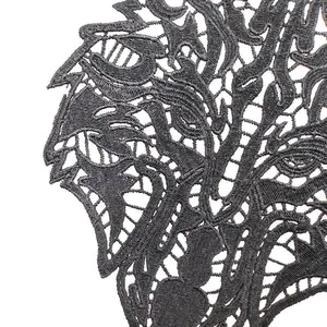 Close-up of black water-soluble lace beast head embroidery with intricate hollow design