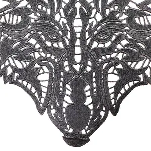 Macro view of black water-soluble lace appliqué with intricate beast head embroidery detail.