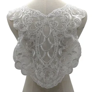 Detailed close-up view of white embroidered lace applique with elegant floral patterns