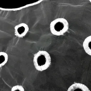 Detailed macro view showing white embroidered circle patterns on sheer black organza lace