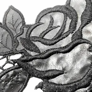 Close-up macro detail of heavy black rose embroidery on silver PU leather applique patch