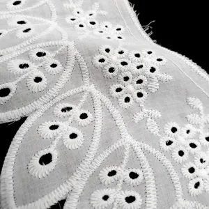 Close-up macro view of detailed white cotton eyelet embroidery lace with floral patterns