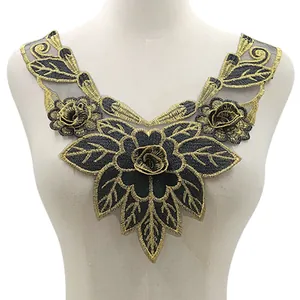 Dettaglio di applique floreale in ricamo oro pesante con rosa 3D su colletto in rete nera.