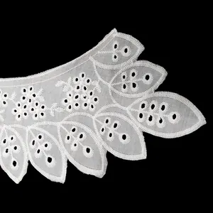 Detailed macro view of white cotton embroidered lace collar with delicate eyelet cutouts