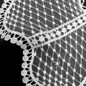 Macro detail view of white water-soluble lace embroidered collar with fine mesh textures