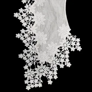 Detailed macro view of white cotton embroidered lace collar with hollow out floral patterns