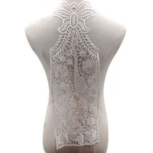 Detailed view of intricate white peacock and floral embroidery on water-soluble lace.