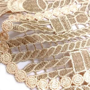 Vue macro détaillée d'une dentelle brodée dorée lourde avec des motifs de roses