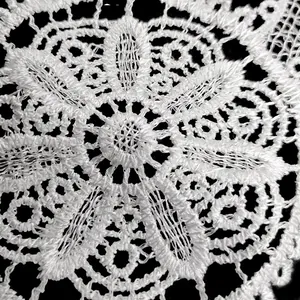 Detailed macro view of white water-soluble lace embroidery featuring an intricate floral pattern