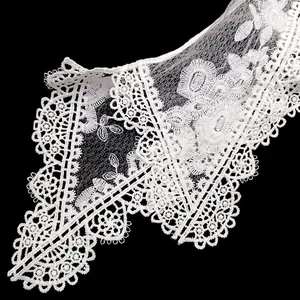 Détail de la broderie en dentelle blanche à double couche avec des motifs floraux