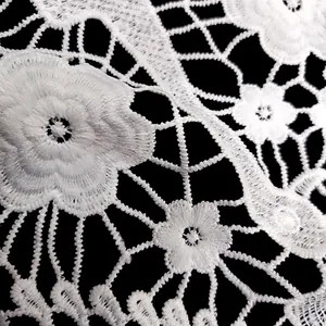 Detailed macro view showing the intricate floral embroidery on white milk silk lace fabric