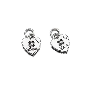 Detailopname van vintage 925 sterling zilveren hartbedels met gegraveerde Love tekst.