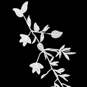 Macro view of white floral lace embroidery showing fine vine and leaf textures on black.