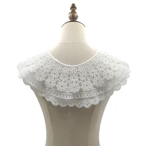 Detalle del cuello de encaje floral blanco bordado con bordes festoneados sobre maniquí