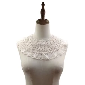 Detalle de un cuello falso de encaje blanco con bordados florales multicapa.