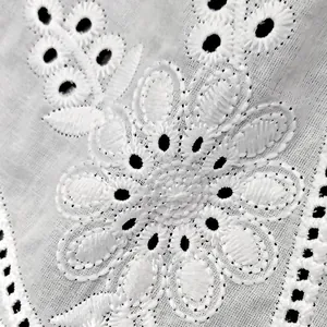 Macro view of intricate white floral eyelet embroidery on cotton lace fabric
