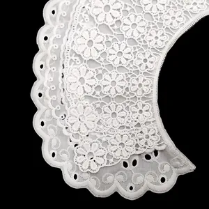 Primer plano de un cuello falso de encaje blanco con bordado floral y detalles calados.