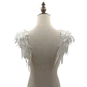 Detailed macro view of white water-soluble lace angel wing appliqués on a mannequin