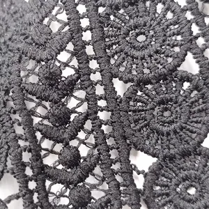 Detalle macro de encaje bordado de seda de leche negra con motivos florales calados.