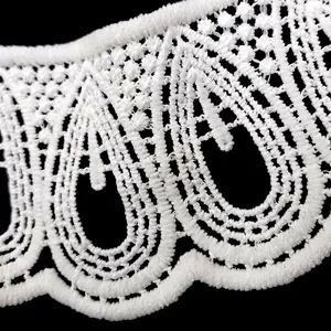 Close-up detail of white milk silk embroidered lace trim with hollowed-out pattern