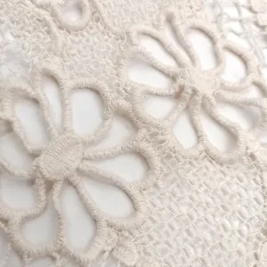 Macro view of white cotton embroidery floral pattern on delicate hollow out lace fabric