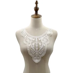 Détail montrant les broderies florales complexes de l'élégant col en dentelle de soie de lait blanc.