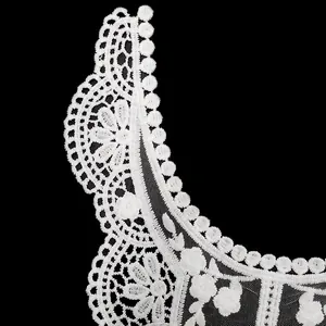Détail d'un col en dentelle brodée de soie de lait blanche avec motif floral sur filet
