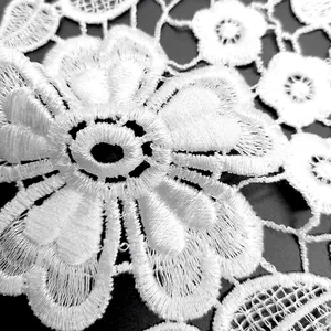 Detailed macro view of white floral lace embroidery with 3D hollow needlework texture