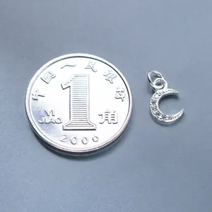 Macro detail view of 925 silver moon pendant with stones next to a coin for scale