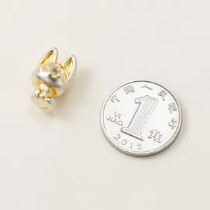 Detailansicht einer Fuchs-Perle aus 999er Sterlingsilber mit Goldakzenten neben einer Münze