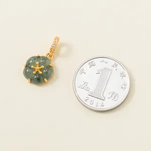 Detailed view of green jade flower pendant with gold-plated bail next to a coin for scale
