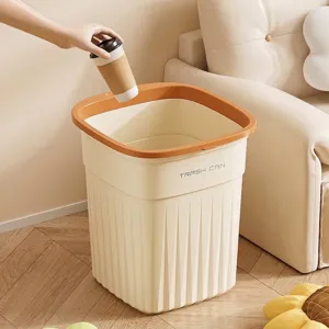 Cream style square trash can with orange pressure ring shown in a cozy living room setting.