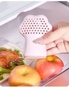 Compacte roze kattenpoot ontgeurder geplaatst in een koelkast naast verse rode appels