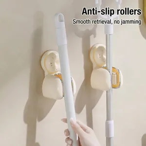 Wall-mounted mop holder with suction cup and anti-slip rollers for broom storage.