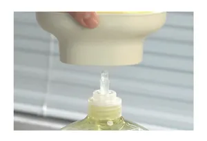 Makroaufnahme einer cremefarbenen Seifenspenderpumpe, die an eine Flasche angeschlossen wird