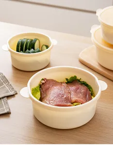 Stackable plastic food storage containers with raw meat and sliced cucumbers inside