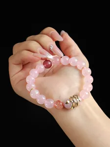 Detailed close-up of rose quartz beaded bracelet with a golden snake charm against black