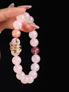 Detailed view of a rose quartz beaded bracelet featuring a crafted gold snake charm.
