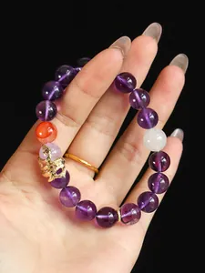 Close-up detail of a purple crystal beaded bracelet featuring a golden snake charm.