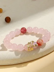 Detailed macro view of pink rose quartz bead bracelet featuring a golden snake pendant