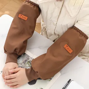 Brown waterproof canvas oversleeves for work and home protection on white jacket