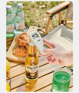 Detailed view of a hand using a white magnetic multi-functional bottle opener on a beer bottle