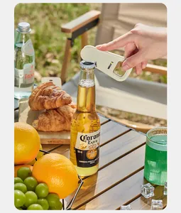 Close-up of a cream-colored magnetic fridge magnet bottle opener being used on a beer bottle