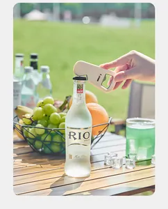 Macro view of a portable magnetic bottle opener opening a cocktail bottle outdoors.
